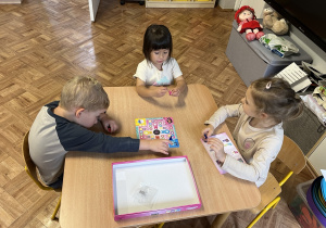 Dzieci grają w grę planszową przy stoliku