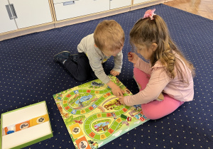 Dzieci grają w grę planszową na dywanie