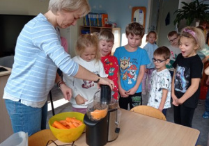 Dzieci z pomocą nauczycielki robią sok