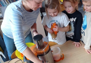 Dzieci z pomocą nauczycielki robią sok