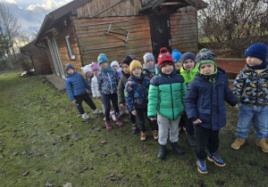 Dzieci stoją parami przed chatką