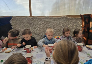 Dzieci jedzą posiłek przy stolikach