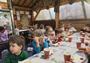 Dzieci jedzą posiłek przy stolikach