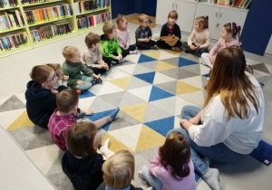 Dzieci siedzą w kole na dywanie