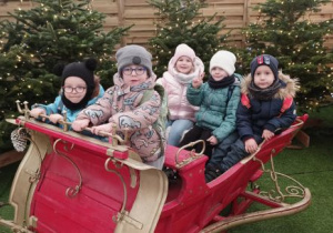 Dzieci siedzą w saniach mikołaja