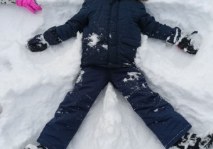 Chłopiec robi orzełka na śniegu