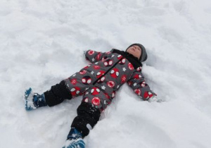 Chłopiec robi orzełka na śniegu