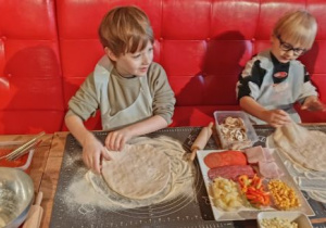 Chłopiec formuje placek pizzy