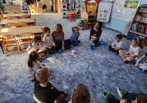 Dzieci siedzą w kole podczas zajęć