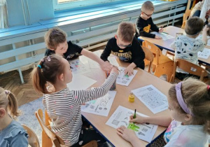 Dzieci wykonują kartę pracy przy stoliku